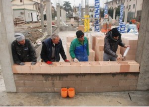 Una squadra di ragazzi trentini posa i mattoni rettificati per costruire il Centro servizi Val di Non